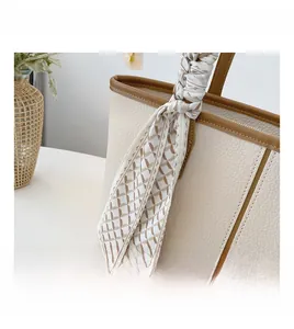 Gros plan d'un sac cabas en cuir grainé blanc cassé avec un foulard en soie décoratif
