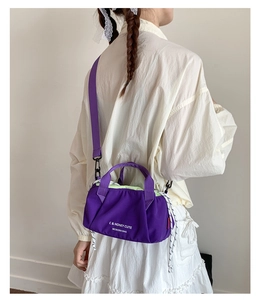 Detail of purple nylon mini crossbody bag showing text print and sporty drawstrings