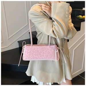 Pink leopard print baguette bag with bow ribbons worn by model in casual outfit