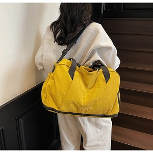Detail of waterproof nylon gym bag in bright yellow with adjustable black shoulder strap