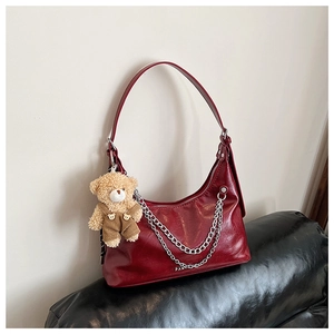 Detail der weinroten PU-Schultertasche mit Silberketten und einem Plüschbär-Anhänger