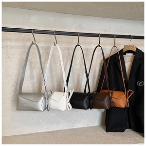 Row of leather crossbody bags in five colors featuring side bow detail and metallic hooks