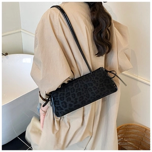 Detail of black leopard print shoulder bag with side bow detail on a beige coat