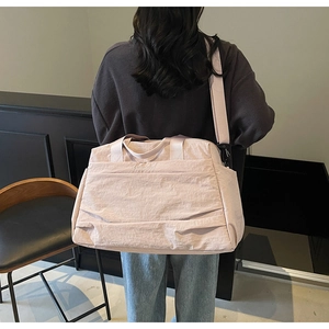 Détail du sac de voyage en nylon rose avec poignées solides et bandoulière réglable de sac