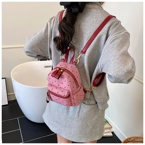 Detail shot of mini pink backpack featuring red stripes, heart patterns and red straps