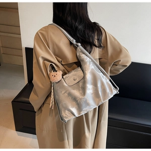 Silver metallic pleated tote bag with cute brown bear charm shown on a model