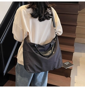 Detail der großen schwarzen Nylon-Umhängetasche mit Multi-Pocket-Design am Model