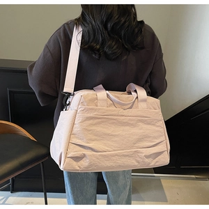 Détail du sac de voyage en nylon rose clair imperméable avec bandoulière réglable et broderie