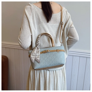 Modèle avec sac seau bleu clair texturé, poignées marron et foulard pied-de-poule