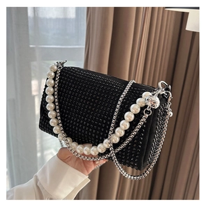 Detailed macro view of black rhinestone Boston bag with pearl and metal chain straps