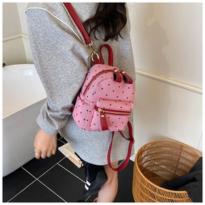 Pink mini backpack detail with red hearts and leather straps worn by model in bathroom