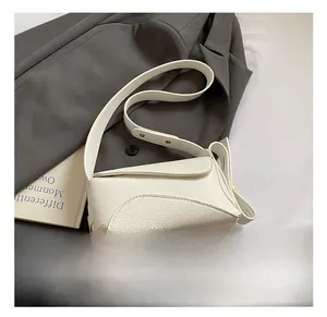 Detail of white litchi pattern leather shoulder bag on grey suit jacket with magazine