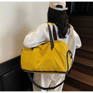 Detail of waterproof nylon gym bag in bright yellow with durable black shoulder straps