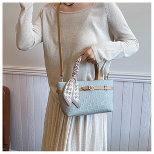 Détail du sac seau bleu clair avec texture géométrique et foulard en soie sur l'anse