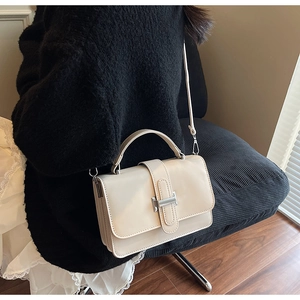 Chic cream leather handbag with gold H buckle shown worn as a crossbody shoulder bag