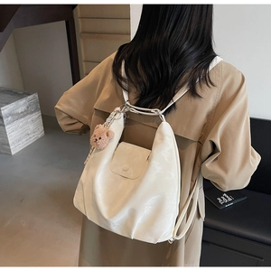 Detail of soft cream PU leather backpack with teddy bear charm on model's back