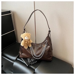 Detailaufnahme der dunkelbraunen Lackleder-Hobo-Tasche mit Silberkette und Bärchen