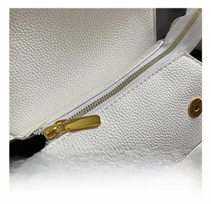 Close-up of golden zipper and magnetic snaps on white pebbled leather shoulder bag
