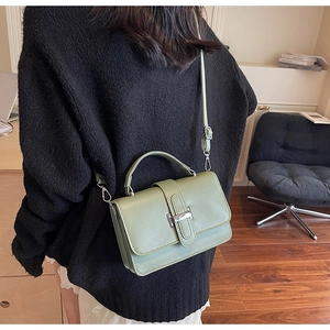 Detail of avocado green leather handbag with silver clasp shown on a model