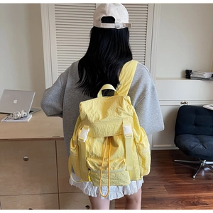 Détail d'un sac à dos imperméable jaune vif avec boucles blanches et cordon de serrage