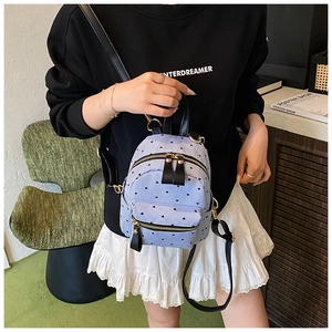 Detail of mini backpack featuring light blue stripes, heart pattern and leather straps