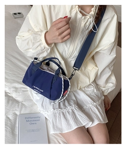 Close-up of navy blue canvas crossbody bag with white lettering and wide strap detail