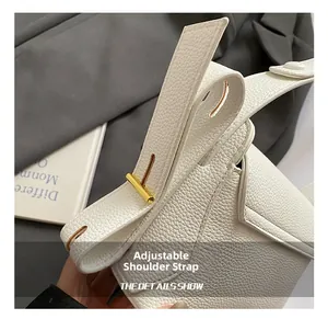 Detail showing the adjustable white lychee leather shoulder strap with golden buckle