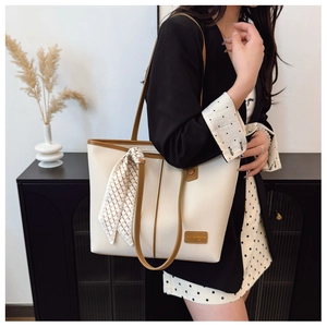 Chic beige tote bag with litchi texture and silk scarf detail shown on shoulder