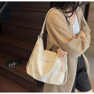 Detail of soft cream PU leather tote bag with plush bear charm and wide strap
