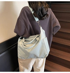 Detail der mintgrünen Canvas-Tasche mit breiten Griffen und verstellbarem Riemen am Modell