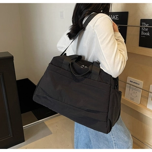Détail d'un grand sac de voyage noir en toile avec poignées larges et poche latérale pratique
