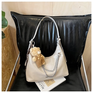 Detailansicht cremefarbene Halbmond-Tasche mit Silberkette und Teddybär-Anhänger