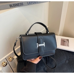 Detail of black rectangular crossbody bag featuring a silver metal H-shaped buckle closure