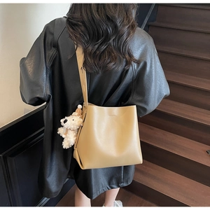 Detail of khaki PU leather bucket bag with wide strap and cute plush bear charm