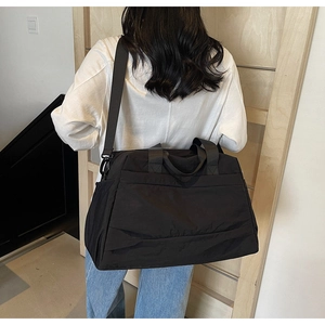 Vue de dos d'un mannequin portant un grand sac de voyage noir en nylon sur un chemin en bois