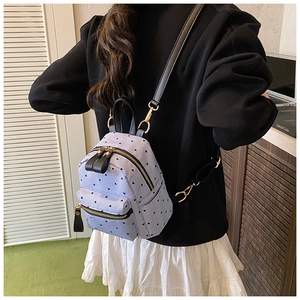 Close-up of a purple mini backpack with heart patterns and gold zipper details