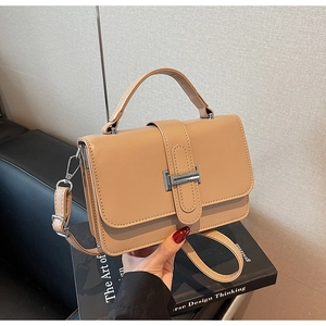 Close-up of tan leather handbag with silver H-buckle and adjustable shoulder strap