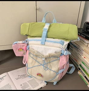 Detail of multi-color pastel backpack featuring mesh pocket and bungee cord system
