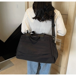 Vue de dos d'un mannequin portant un grand sac cabas en toile noire dans une pièce épurée