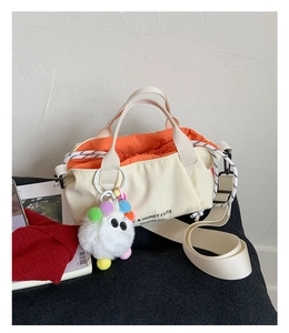 Detail of minimalist canvas bag with orange lining, drawstring closure and plush pendant