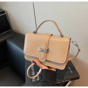 Close-up of minimalist beige faux leather handbag with silver metal buckle detail