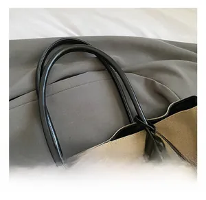 Dettaglio dei manici in ecopelle nera su una borsa tote in tela beige di grandi dimensioni