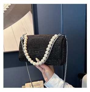 Detail of black rhinestone Boston bag featuring a pearl handle and silver chain strap