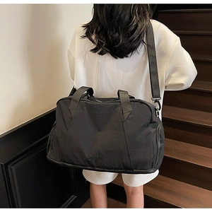 Close-up of a black fitness bag featuring a bottom shoe compartment and shoulder strap