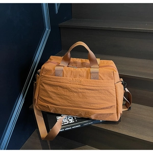 Détail d'un sac de voyage en nylon caramel avec broderie et bandoulière