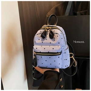 Close-up of heart print mini backpack featuring blue stripes and gold zipper detail