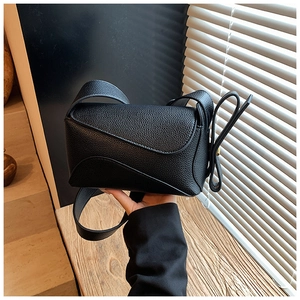 Detailed view of black litchi grain leather shoulder bag with geometric puzzle stitching