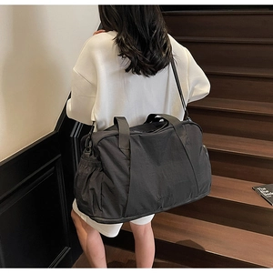 Large black fitness bag shown on model for travel with waterproof nylon and side pockets