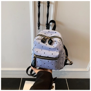 Close-up of mini backpack with blue stripes and black heart patterns held by hand