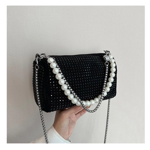 Detail of black rhinestone mini bag featuring large pearl chain and silver strap